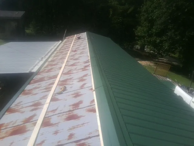 Old rusted panels beside newly installed green metal roofing — Wind Damage Roof Repair by Roofing Brothers in Egg Harbor Township