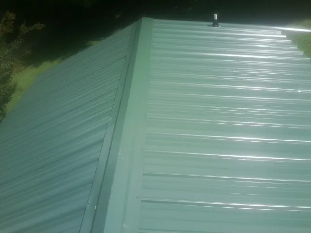 New green metal panels meeting at the ridge of a roof — Flat Roof Repair work by our crew in Egg Harbor Township