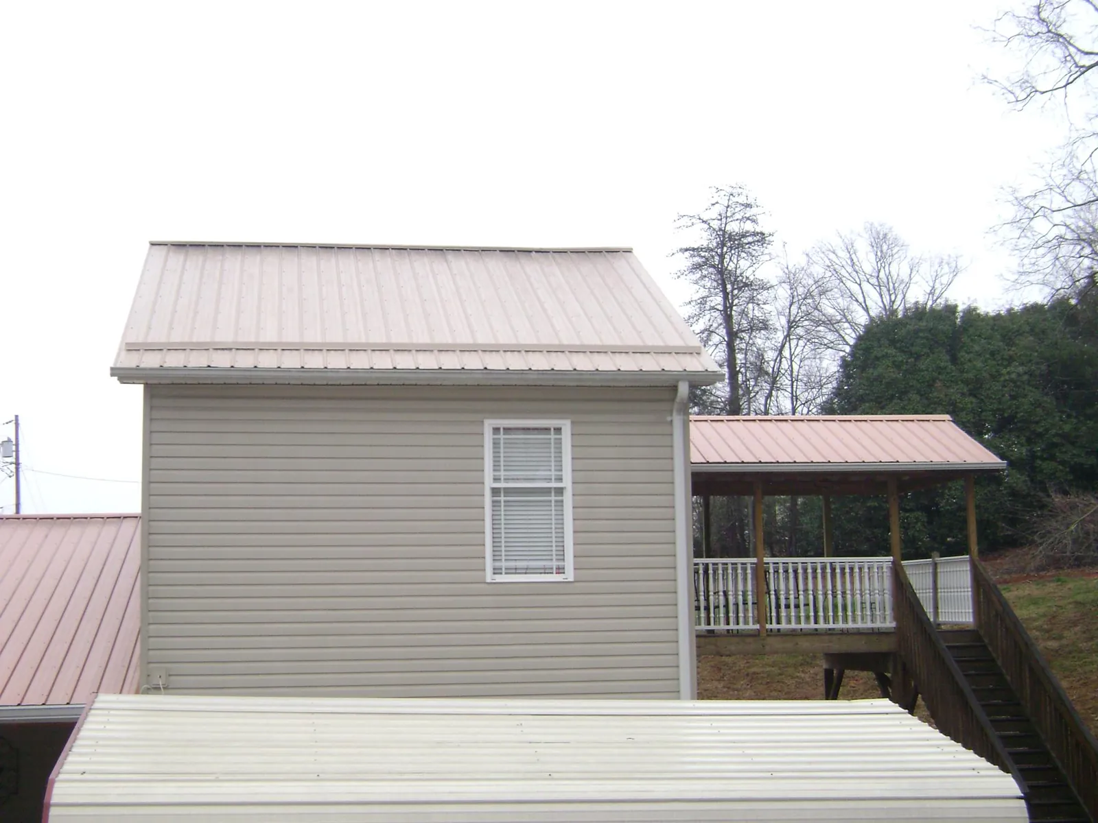 Tan metal roofs on a two story addition and attached porch, from a Roof Replacement job in Egg Harbor Township