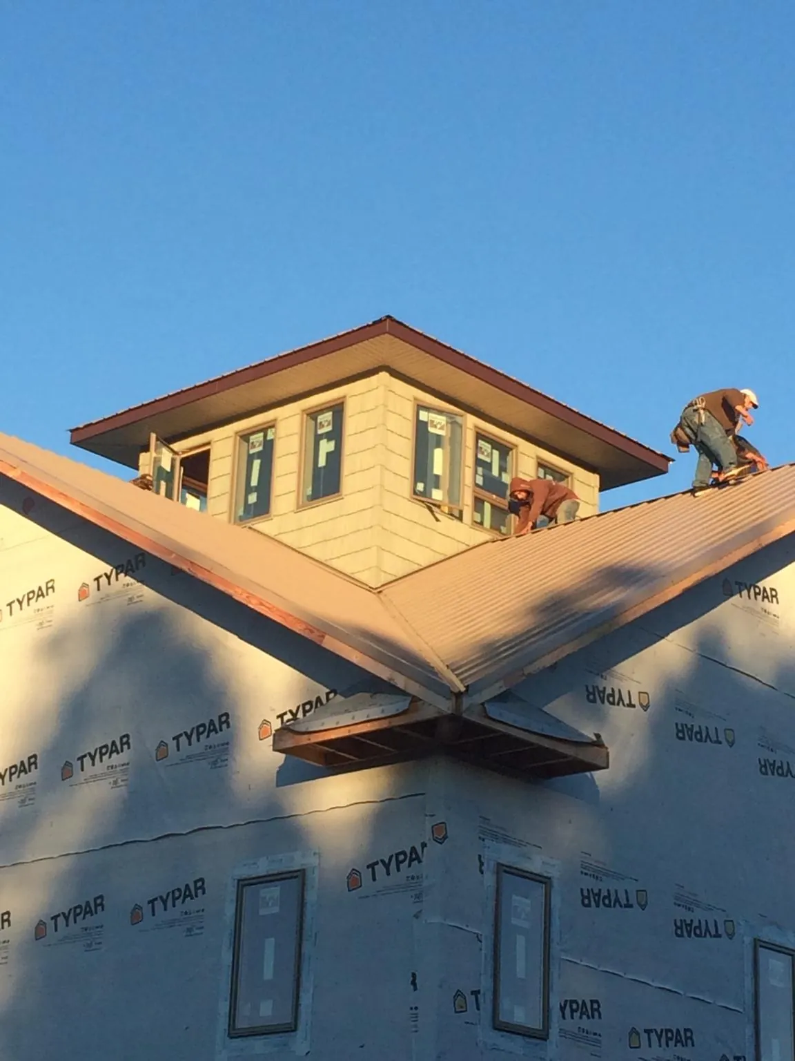 Roofers working around a rooftop cupola on a new metal roof at sunset — Roof Waterproofing in Egg Harbor Township by Roofing Brothers